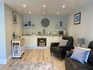 a living room with two couches and a kitchen at Bow Cottage in Bridport