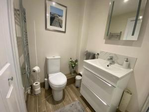 a white bathroom with a toilet and a sink at Bow Cottage in Bridport