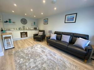 a living room with a black leather couch and a chair at Bow Cottage in Bridport