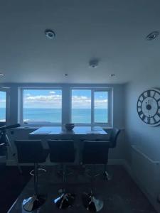 スカーバラにあるPenthouse Flat in Scarboroughのテーブル、椅子、時計が備わる客室です。
