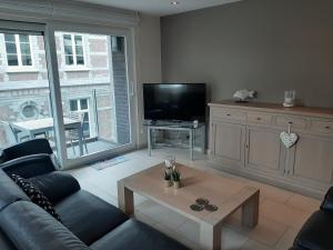 uma sala de estar com um sofá, uma televisão e uma mesa em Vakantieappartement Belle Epoque Blankenberge em Blankenberge