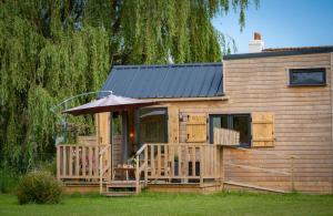 a cabin with a deck and an umbrella at Tiny house au cœur du marais in Saint-Omer