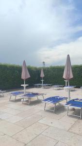 a group of lounge chairs and umbrellas on a patio at Locanda Corte Arcangeli in Ferrara