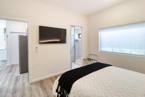 a white bedroom with a bed and a large window at Colina Inn in Escazu