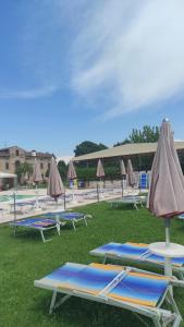a group of lounge chairs and umbrellas on the grass at Locanda Corte Arcangeli in Ferrara