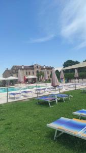 a group of tables and umbrellas next to a pool at Locanda Corte Arcangeli in Ferrara