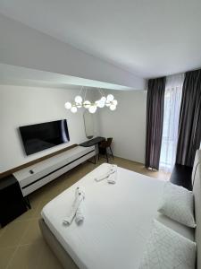 uma sala de estar com uma cama branca e uma televisão em Cozy Apartments em Tirana