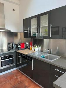 a kitchen with black cabinets and a sink at Appartement vue sur mer, piscine, garage privé in Bormes-les-Mimosas +4 photos