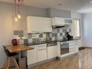 a kitchen with white cabinets and a wooden table at Villa Colonna Appartements in Manosque