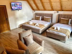 a bedroom with two beds and a couch and a tv at Chalet Kujta in Peje