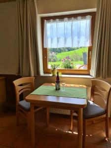 a table with a bottle of wine and a window at Haus Föhrenbach in Schönenberg