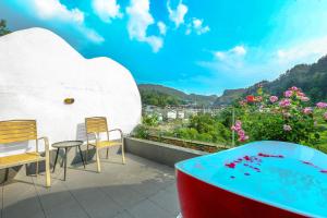 a balcony with a pool and chairs and flowers at Pure House--Free shuttle Service to South Gate of the Forest Park,Attraction Tickets Serivce in advance, Mount View, Nature village and Tranguility in Zhangjiajie