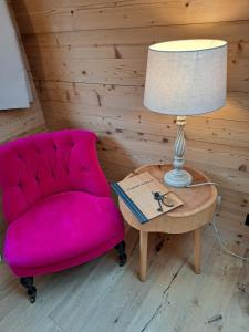 a pink chair and a table with a lamp at Hotel Chesa Staila in La Punt-Chamues-ch