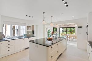 a kitchen with white cabinets and a black counter top at The Manor at Minstrel Court with Hot Tub in Cambridge +49 photos