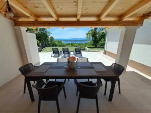 a dining room table with chairs and a wooden ceiling at Apartman Luce in Jadranovo