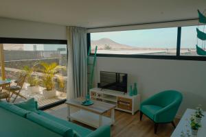 sala de estar con sofá azul y TV en Villa Relajares, en Lajares