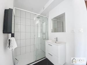 a white bathroom with a shower and a sink at Marine Serenity - Appartement à 50m de la plage in Bray-Dunes +6 photos