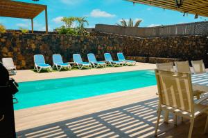 une piscine avec des chaises, une table et une clôture dans l'établissement Villa Relajares, à Lajares