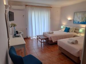 a hotel room with two beds and a chair at Aurora Sol in Luz +37 photos