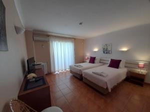 a hotel room with two beds and a window at Aurora Sol in Luz