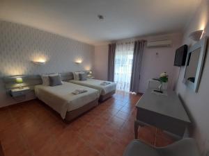 a hotel room with two beds and a desk at Aurora Sol in Luz