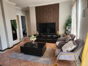 ein Wohnzimmer mit einem TV, einem Sofa und einem Tisch in der Unterkunft The lion Sands Apartment in Pretoria