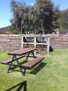 a picnic table in the grass next to a fence at Cabañas Kay Hue in San Carlos de Bariloche