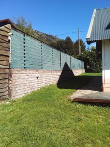 a brick wall with a fence next to a yard at Cabañas Kay Hue in San Carlos de Bariloche