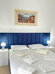 un grande letto con lenzuola bianche e asciugamani sopra di Eleni Guest House a Sarandë