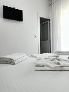 a white bedroom with two beds and a flat screen tv at Eleni Guest House in Sarandë