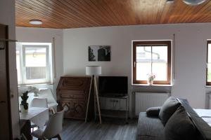 a living room with a couch and a tv and two windows at Metzgerei und Pension Wolz in Langenburg