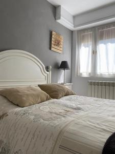 - une chambre avec un grand lit et une tête de lit blanche dans l'établissement Apartamento Zurbarán, à Irún