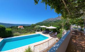 uma piscina com cadeiras e guarda-sóis num quintal em Villa Casa Belvedere near Dubrovnik em Gruda