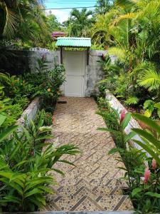 un giardino con passerella in mattoni e garage bianco di chez arlette a Petit-Bourg