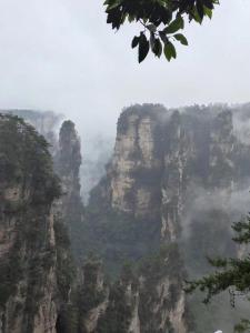 une chaîne de montagnes brumeuse avec des rochers et des arbres dans l'établissement Zhangjiajie Tianmen Mountain Aribadi Inn, à Zhangjiajie