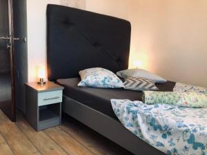 a bed with a black headboard and a night stand at Apartments Jadra in Kučište