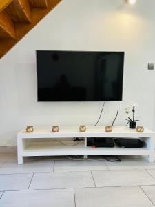 a white entertainment center with a flat screen tv on a wall at Lit Style Dortoir dans un Maison in Bezons