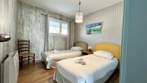 une chambre d'hôtel avec deux lits et une chaise dans l'établissement Appt avec vue EXCEPTIONNELLE sur la baie + garage, au Crotoy