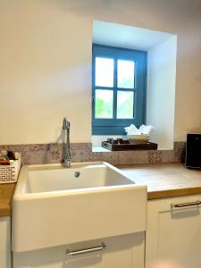 a kitchen with a white sink and a window at La Cassine bis - Havre de paix à Saint Ceneri in Moulins-le-Carbonnel