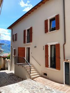 una casa bianca con persiane e scale in legno di CASA CIAO a San Demetrio neʼ Vestini