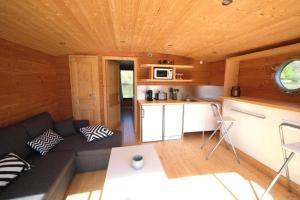 una habitación con sofá y una cocina en una cabaña en Les Cabanes de Lara en Ménesplet
