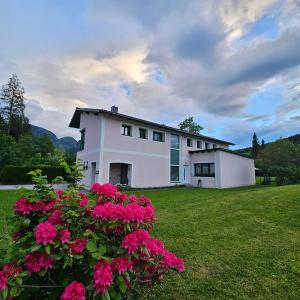 una casa blanca con flores rosas en un patio en Ferienwohnung Blick ins Grüne, en Rossleithen