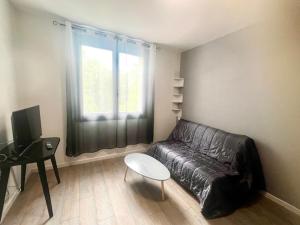 a living room with a leather couch and a window at Résidence ATIPYC in Marssac-sur-Tarn