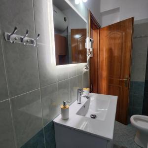 une salle de bain avec un lavabo, des toilettes et un miroir dans l'établissement SunSea apartment, à Saranda 2 autres photos