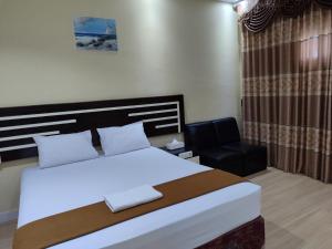 a bedroom with a large bed and a chair at H.V HOTEL BANDARA in Gorontalo