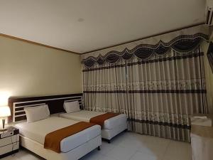 una camera d'albergo con due letti e una finestra di H.V HOTEL BANDARA a Gorontalo