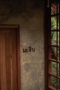una señal en el costado de una pared al lado de una puerta en Woo Ma Ca Moo, en Chiang Mai