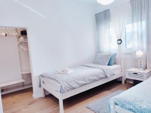 a white bedroom with a bed and a window at Lumani Apartment Zagreb with FREE Parking in Zagreb