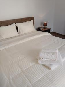 een wit bed met twee handdoeken erop bij BM Apartman in Gornji Milanovac