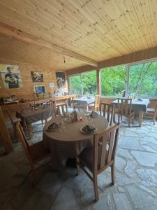 ein Esszimmer mit Tischen, Stühlen und Fenstern in der Unterkunft Magic Space Petros Skafias in Shkodra